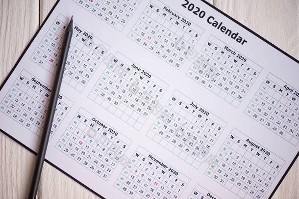木制背景图上2020年日历和铅笔的顶视图