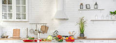 现代时尚厨房内部的蔬菜和水果在桌子上。明亮的白色厨房，有家用物品。健康生活方式的概念.