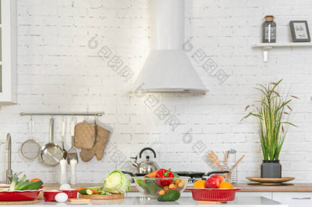 现代时尚厨房内部的<strong>蔬菜</strong>和水果在<strong>桌子</strong>上。明亮的白色厨房，有家用物品。健康生活方式的概念.