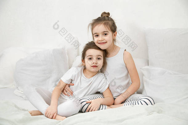 两个可爱的妹妹抱在卧室的床上。家庭<strong>价值观</strong>和儿童友谊的概念.