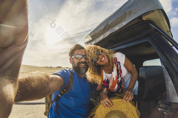快乐而美丽的年轻的高加索人夫妇与他们一起享受并拍了一张圆滑的照片，以及屋顶上有帐篷的汽车- -度假的另类交通工具和快乐的人们免费在一起