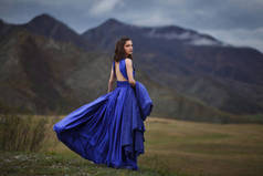 一个穿着华丽蓝色衣服的女孩在山里散步.