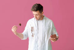 衣衫褴褛的男人吃着彩色背景的巧克力蛋糕