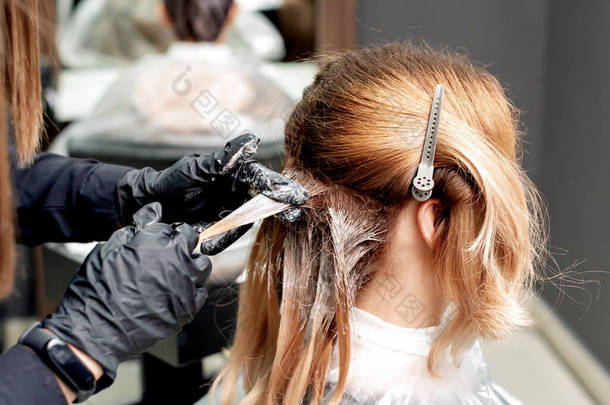 <strong>理发师</strong>的手正在染发的女人穿着黑色手套在发廊.染发.