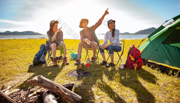 在秋天的林间小径上搭起一个户外帐篷后，一群亚洲登山者正坐在那里享受着喝一杯的乐趣。远足、远足、团队、森林、露营、活动概念.