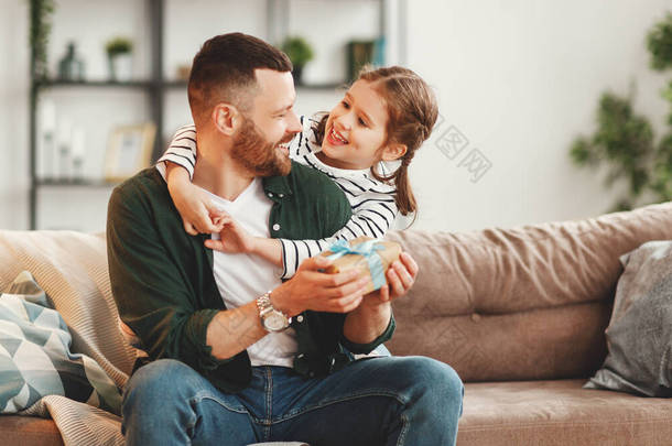 Happy young man with gift in hand and adorable little daughter embracing andlooking at each other wh