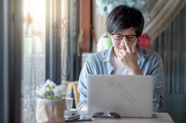 亚洲自由职业男子调整眼镜使用笔记本电脑在咖啡店。穿着休闲装的商人参加在线会议或电子通勤。远程工作从任何地方。聪明地<strong>运用</strong>技术