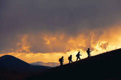一群徒步旅行者在雄伟的落日下漫步在群山中