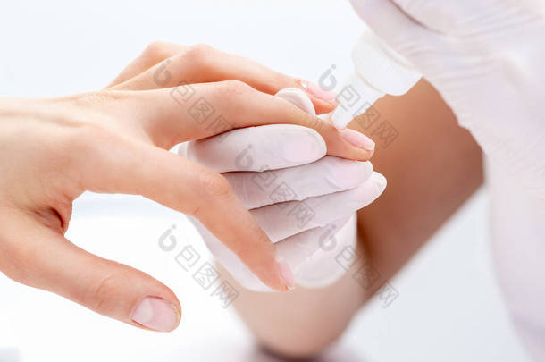 指甲美容师的手用胶水贴住妇女的指甲.美容师使用修指甲工具.