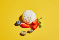 新鲜美味的冰激凌球，带有薄荷叶和黄色背景的浆果