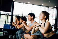 一群身穿运动服的亚洲年轻人蹲着，在体育馆里锻炼.