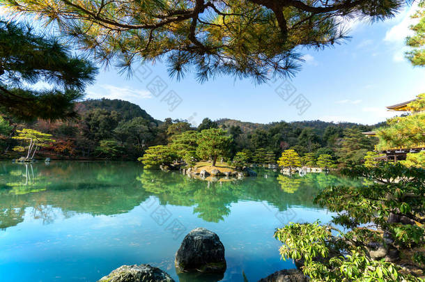 园林绿化精美的日本松木，石园，清澈的湖水，蓝天下的金甲寺，旁边是金亭旅游地标