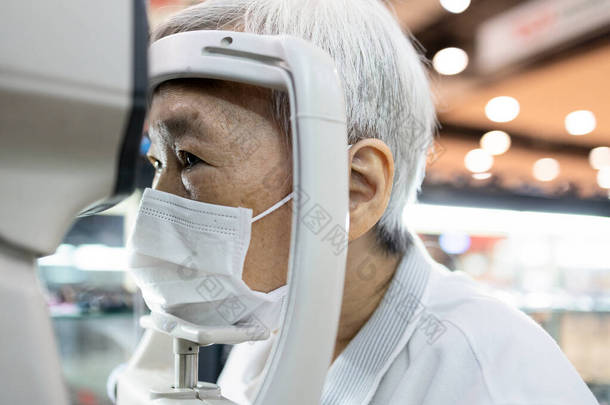 亚洲老年妇女利用眼压仪检查视力，老年病人检查视力，眼科医生检查视力，视力问题，眼科诊所的保健