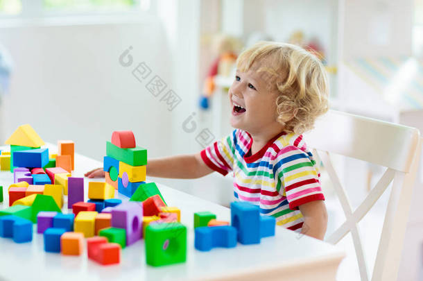 孩子玩彩色玩具块。小男孩用方块玩具建造塔楼。幼儿教育和创意玩具和游戏。婴儿在白色的卧室里用彩虹砖。在家的儿童.