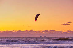 极限运动风筝冲浪，货轮在地平线上。日落时在谢文宁根的海里冲浪.