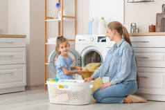 妈妈和小女儿在家里洗衣服