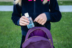 年轻的女学生拿着洗手药瓶重新打开。重返校园，新的人生观. 