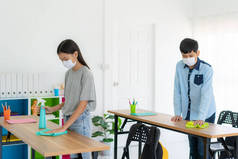 亚洲小学生戴口罩，防止科维德19型流感在课堂上爆发，并使用擦拭和芦荟喷雾清洗餐桌，以消除污染的机会.