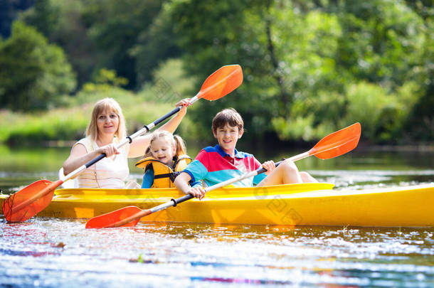 在皮划艇上划桨的孩子。孩子们夏令营。皮划艇和独木舟与家人。独木舟上的孩子乘坐皮划艇的家人。放暑假的<strong>野生</strong>自然和水的乐趣。露营和捕鱼.