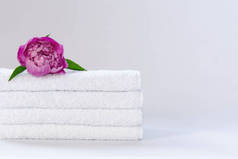 四个白色整齐折叠的毛巾布，背景浅浅的粉色牡丹花