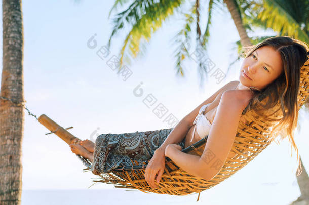 迷失在梦中的女孩在热带岛屿海滩棕榈树间的吊床上荡秋千