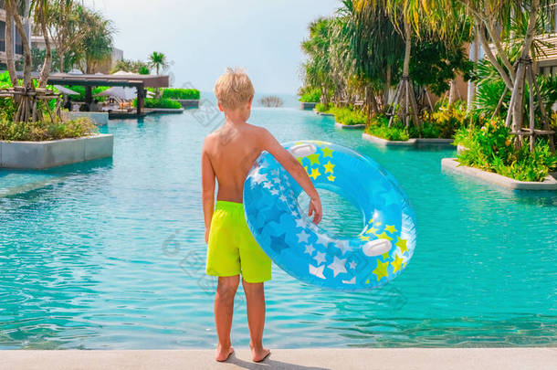 小男孩站在游<strong>泳池</strong>边，手里拿着一个<strong>蓝色</strong>和黄色的游<strong>泳池</strong>。暑假、旅游、旅游、度假等概念.旅馆业复制空间横幅.