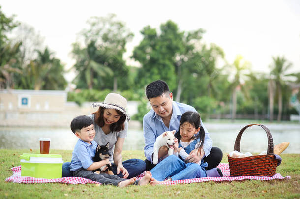 一个亚洲家庭和一只希巴因纽狗玩耍。家庭有父亲、母亲、<strong>儿子</strong>、<strong>女儿</strong>。在花园里野餐.