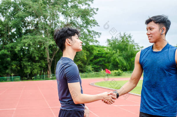 两名男子运动员站在那里握手欢呼,建立起良好的友谊.在去体育场跑步之前。复制空间.