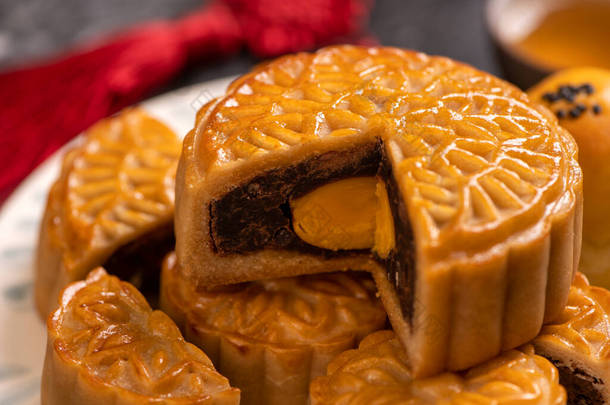 为<strong>中秋节</strong>烤的<strong>美</strong>味蛋黄糕点月饼，背景为黑色石板黑色。中国节庆食品的概念，闭合，复制空间.
