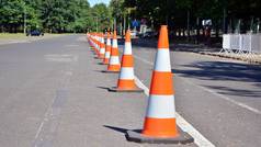明亮的橙色交通圆锥站在一排沥青路面上