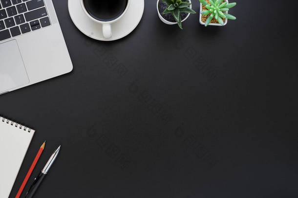 上图为黑色写字台的顶部视图，键盘为笔记本电脑，笔记本电脑为办公室用品。商业和金融概念。工作场所，有空白复制空间的平面布局.