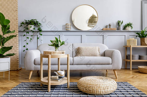 斯堪的纳维亚客厅内饰有设计灰色沙发、木制咖啡桌、热带植物、架子、镜子、家具、<strong>格子</strong>床、茶壶、书籍和精致的个人装饰.