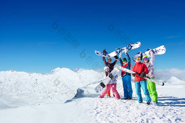 一大批年轻的雪人把雪板举过头顶，站在高山顶上