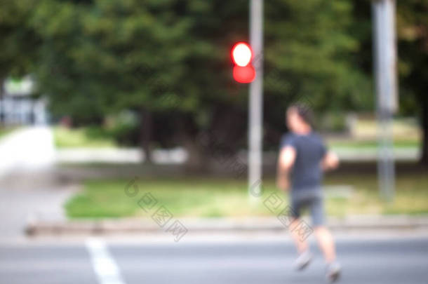 模糊的背景。一个男人在红绿灯下穿过街道.信号转红后，行人过了马路。行人违反交通规则.