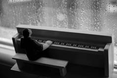 在雨中一个人在玻璃后面弹钢琴的木制形象