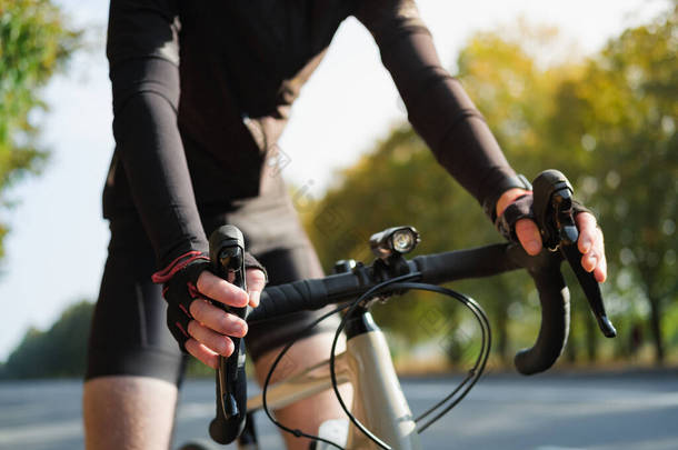 一个骑自行车的手躺在公路自行车的把手上。户外自行车、自行车运动训练