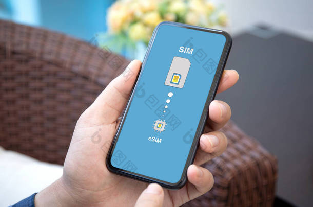 男子手持电话，在房间里的eSim上用Sim卡<strong>替换</strong>
