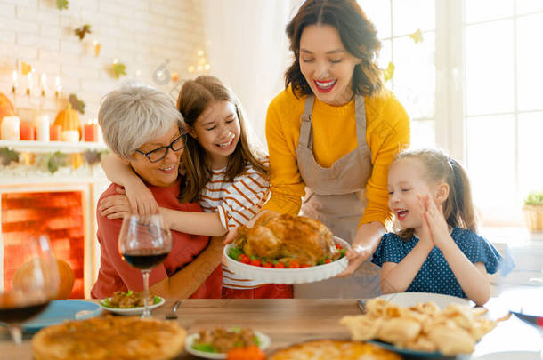 感恩节快乐！秋天的宴会。一家人坐在桌旁庆祝节日.传统的晚餐。祖母、母亲和女儿.