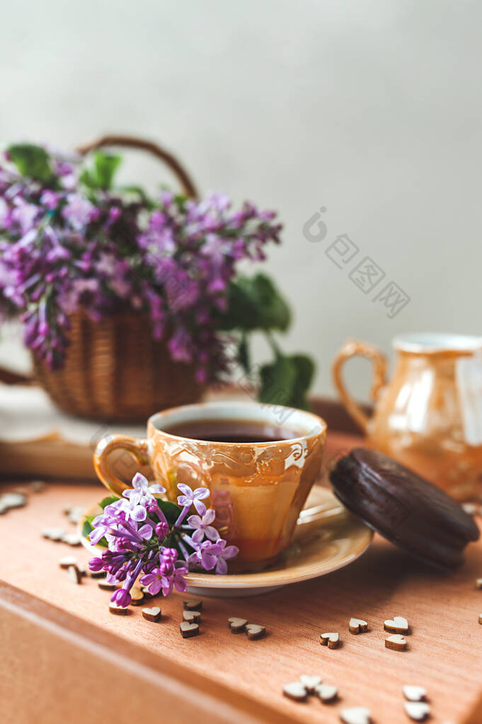 温馨的茶话会在繁茂的鲜花中举行。金瓷杯，红茶，巧克力蛋糕，紫丁香花，装在柳条篮里，木制托盘上装饰着心