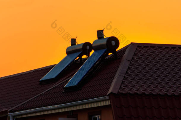 日落时分，住宅屋顶上的太阳能热水器。住房可再生能源