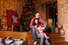 妈妈和爸爸和他们迷人的小女儿在装饰过的圣诞工作室里摆姿势。新年照相会