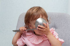 可爱的小女孩用大勺子吃饭.饥饿有趣的婴儿。厨房用具.