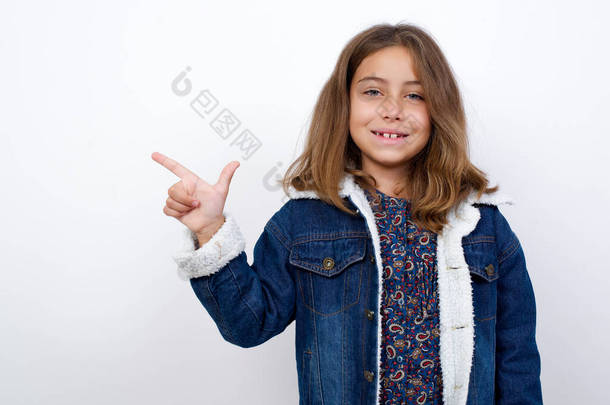 白种人小女孩，蓝眼睛漂亮，身穿斜纹棉布夹克，站在孤立的白色背景上，用手指指尖中国手语B中的第八位.