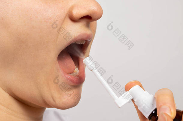 一个人在他的<strong>喉咙</strong>里喷了一种咳剂- -一种防止喉炎和咽炎的防腐剂。药物、治疗和病人的治疗。往嘴里喷药