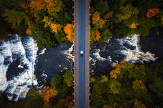 美丽的秋天从空中俯瞰着一个人躺在废弃的铁路桥上，穿过翁托纳贡河，俯瞰着森林下美丽的阿盖特瀑布.