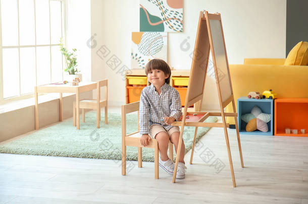 可爱的小男孩在幼儿园的画架旁边