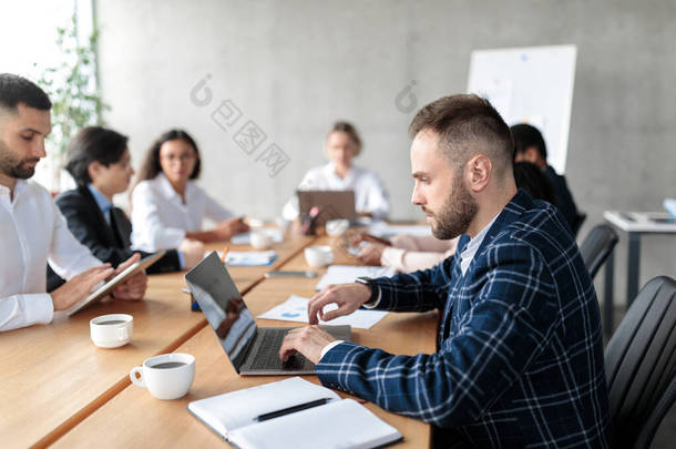 商务人员在现代办公场所开会时使用笔记本电脑