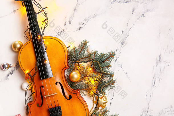 浅色背景上有圣诞彩灯和装饰的小提琴