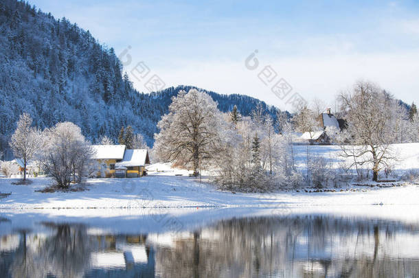 宜人的冬季风景：反光湖、房屋、雪树、高山
