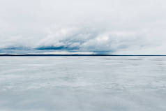 冬季风景。冰封的冰雪覆盖的湖景。后面是森林。暴风雨的晚云。俄罗斯卡累利阿Onega湖